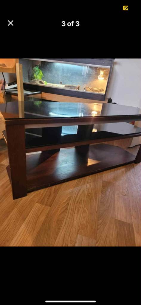 Wooden TV stand with two glass shelves. 