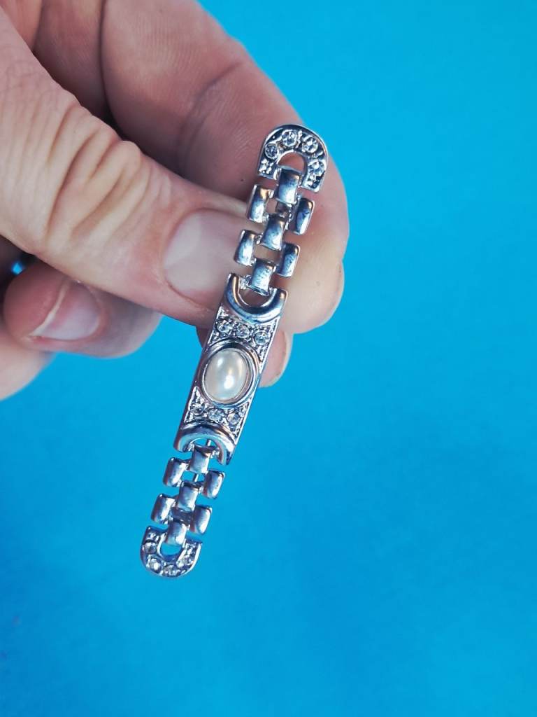 Vintage This is a pearl and diamond or cubic zirconia link bracelet in a silver-toned metal finish. 