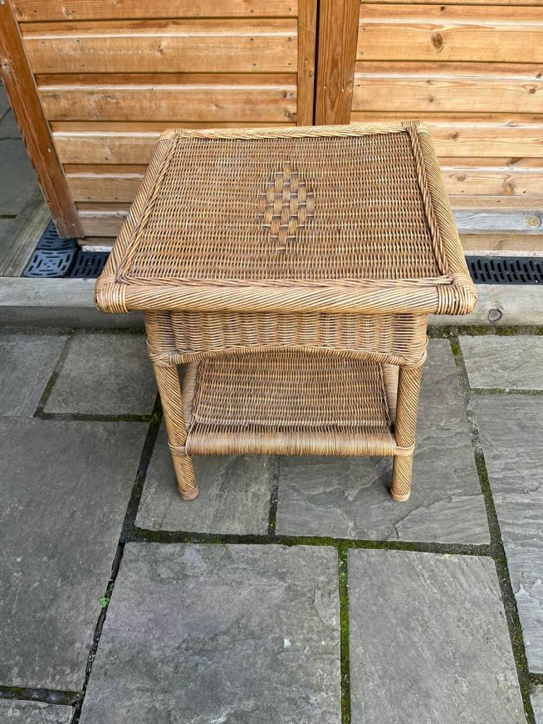 A square four legged wicker table with useful under shelf.