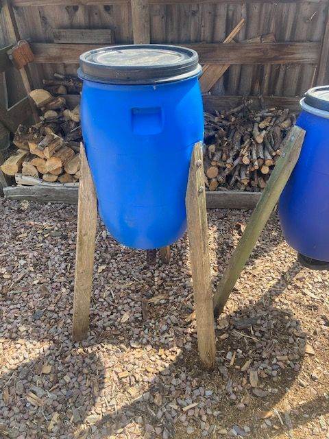 Two DIY poultry or game bird feeders made from repurposed plastic drums.