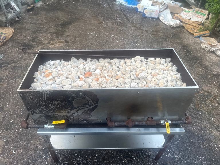 Commercial gas lava rock BBQ chargrill in solid working condition.