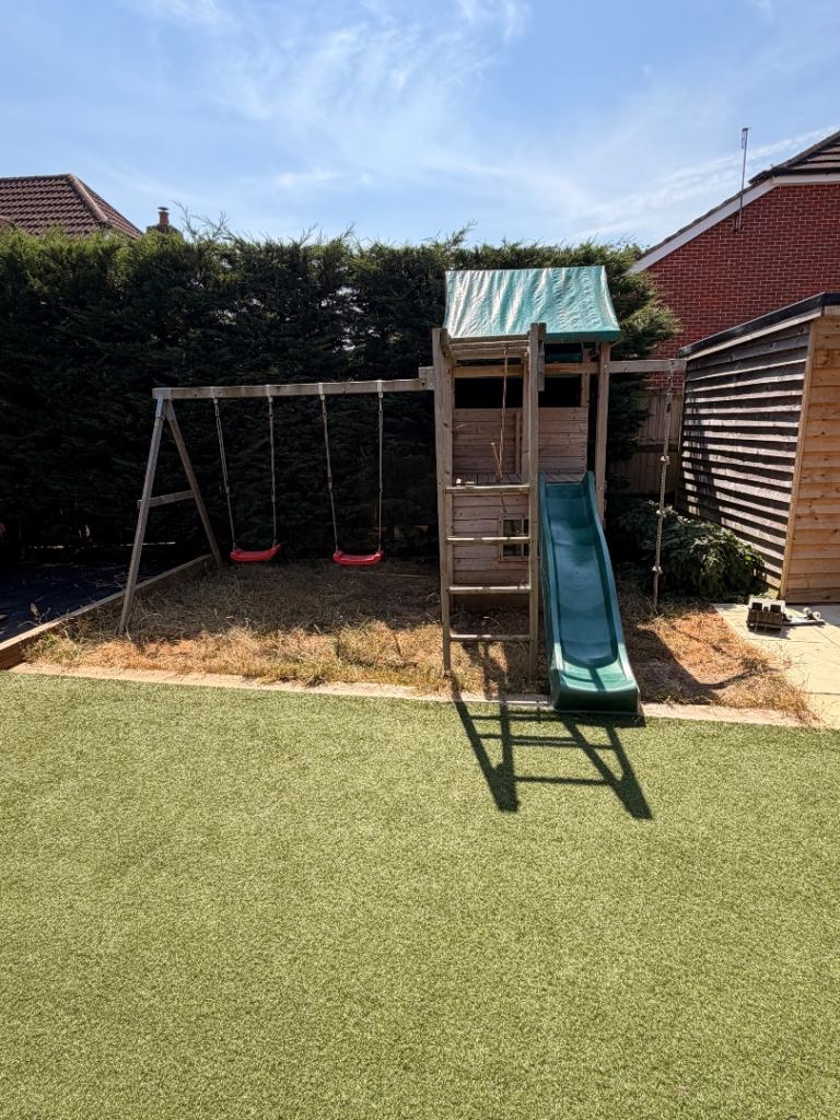 Children’s wooden climbing frame with slide and swings