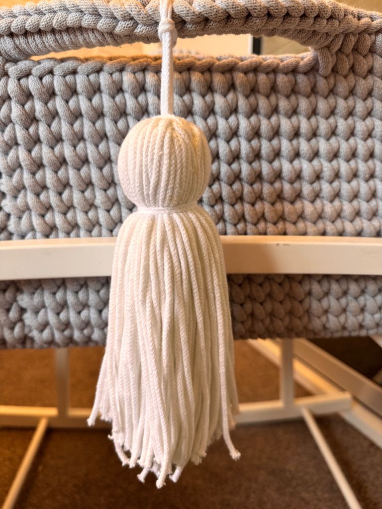 Light grey crochet crib with white wooden stand 