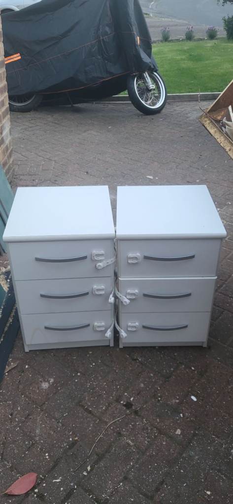 Pair of white bedside tables with three compartments each.
