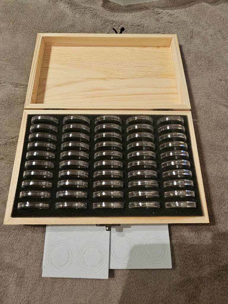 50 coin capsules in wooden box.