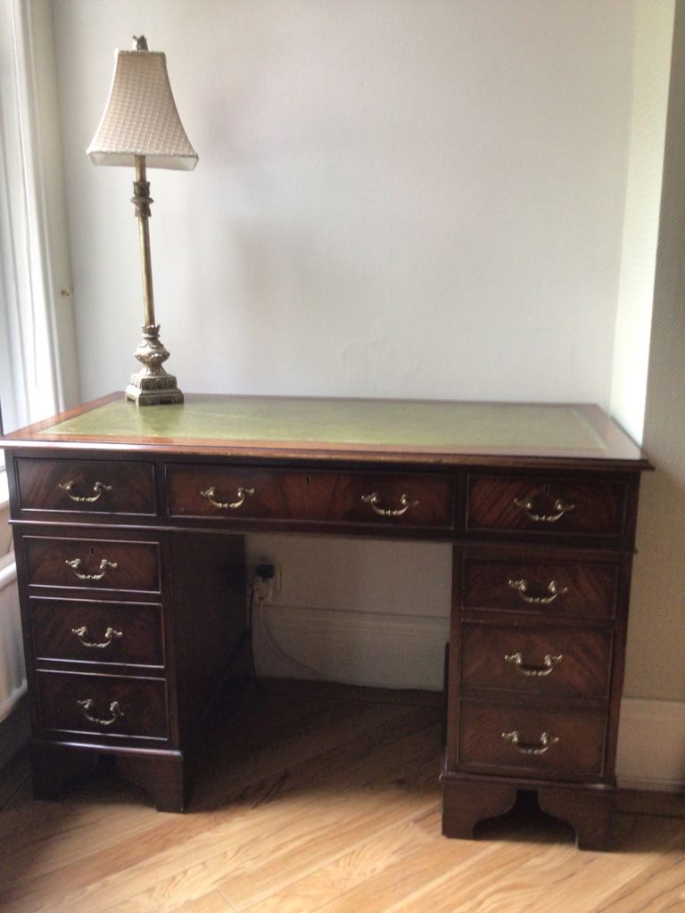 Reproduction leather topped mahogany writing desk and green leather Captains chair.