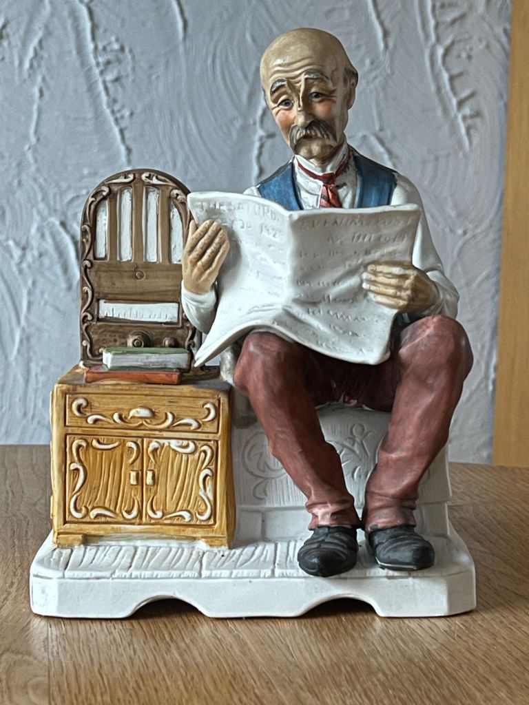 Old Man Reading Newspaper And Listening To Radio 