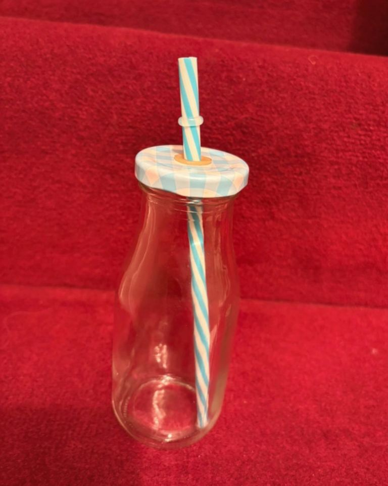Unused glass drinking bottle with blue and white matching straw and lid