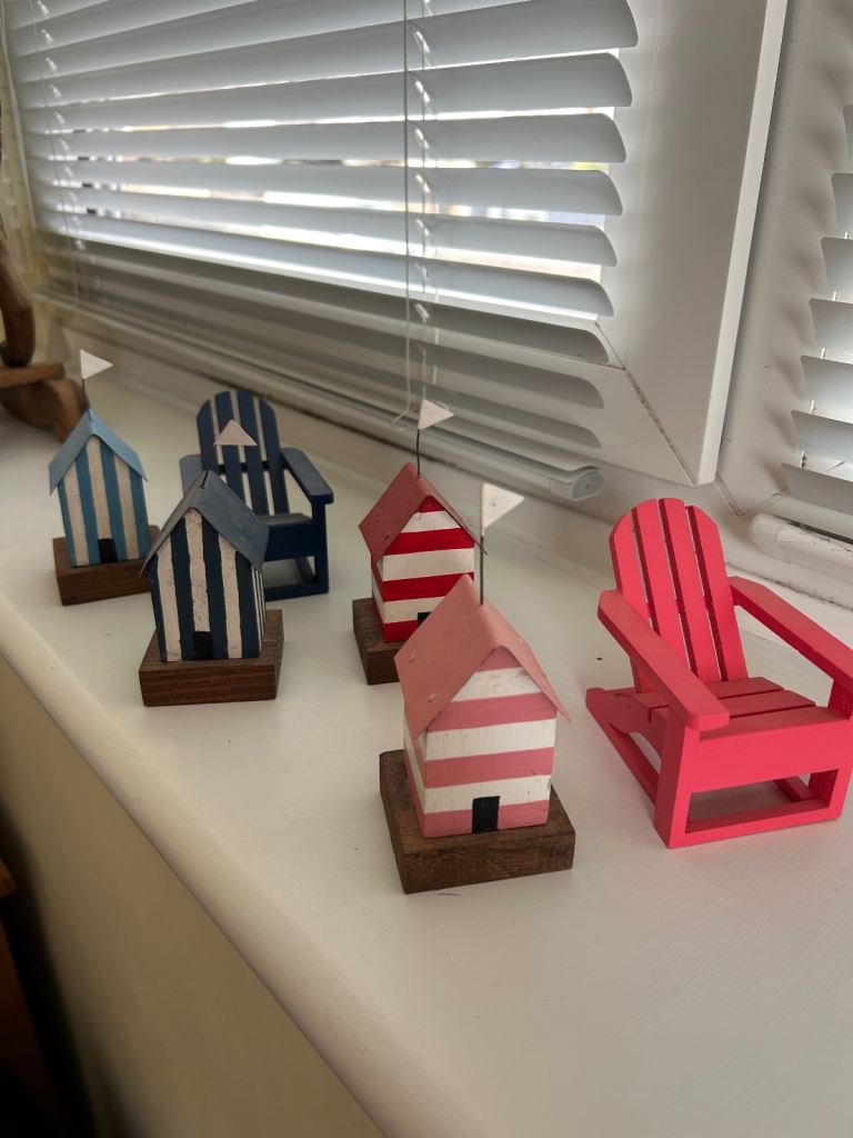 Collection of small wooden beach huts & deck chairs 