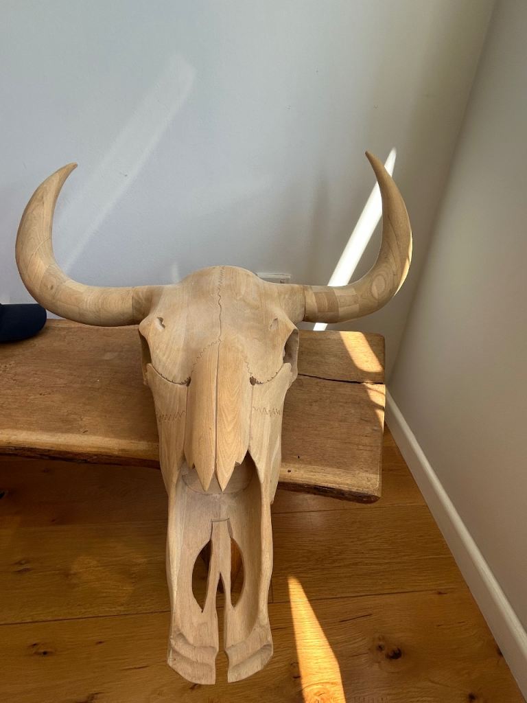 A large hand carved wooden bull skull