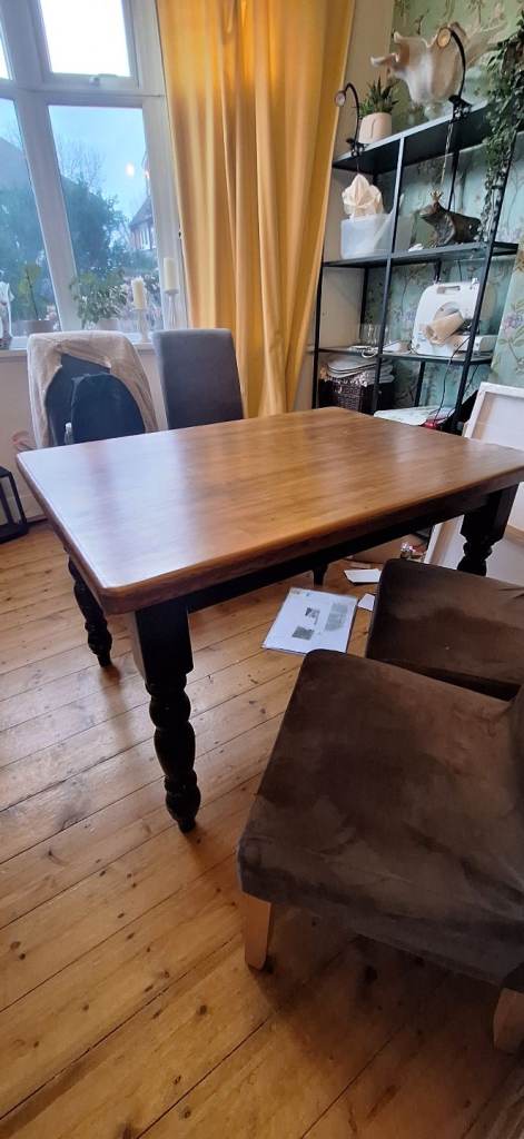 Farmhouse style solid wood table with painted legs and stained top finish 
