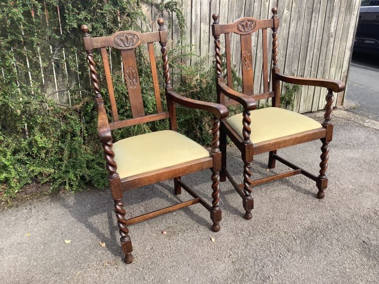 Two Jacobean oak framed open arm upholstered cotton barley twist carver chairs 