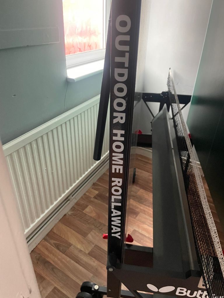 Table tennis table with net , bats and balls.