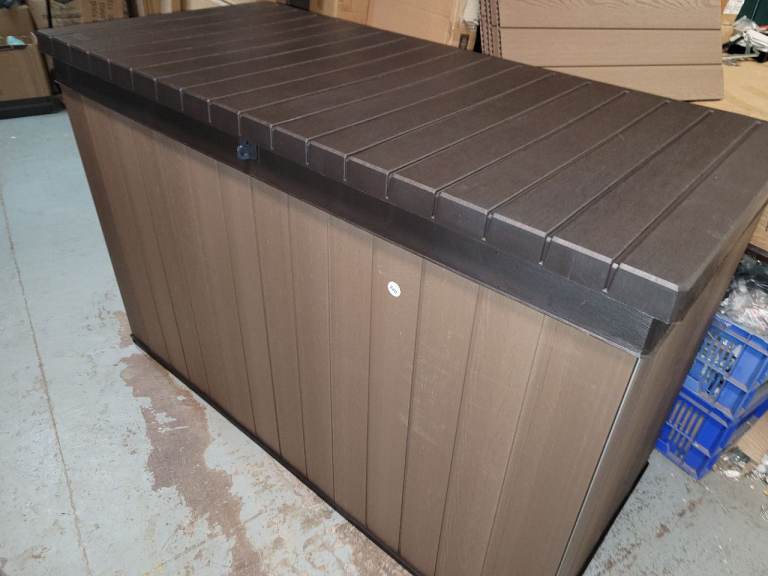 A new brown plastic Keter Darwin storage box keeps garden cushions , tools etc 