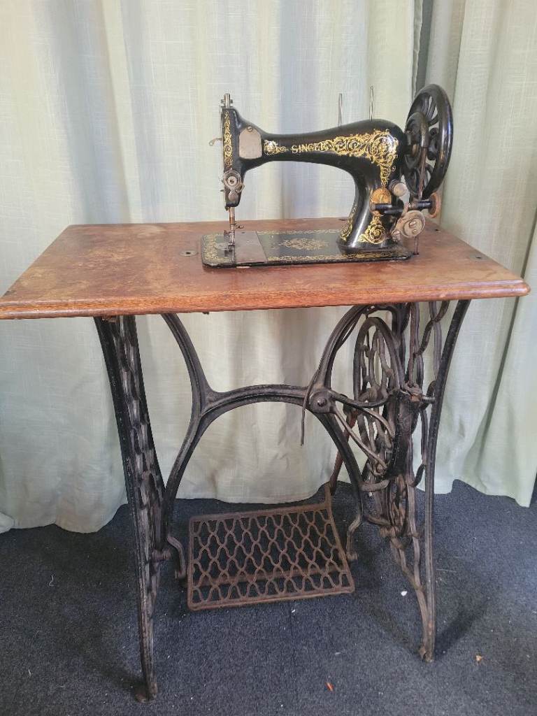 Vintage Singer Sewing Machine with Ornate Treadle Base and Wooden Top Cover