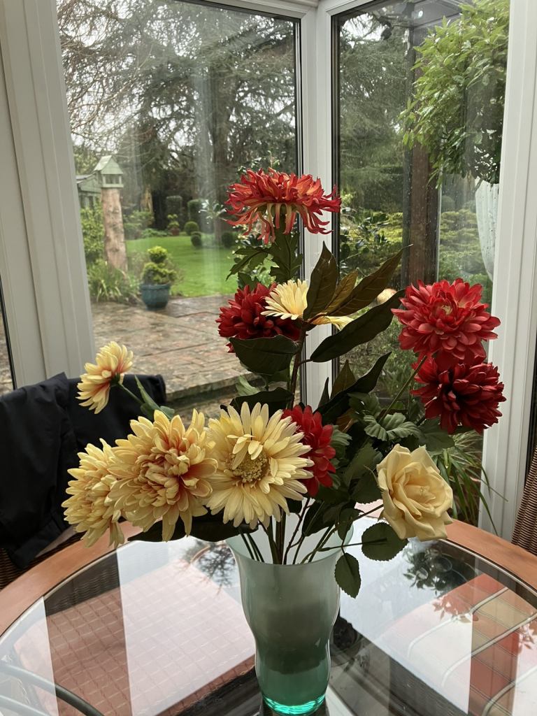 Green glass vase and faux flower display. Collect Chichester