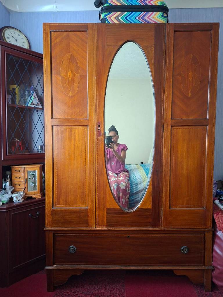 Large antique wooden wardrobe with an oval mirror door and a bottom drawer